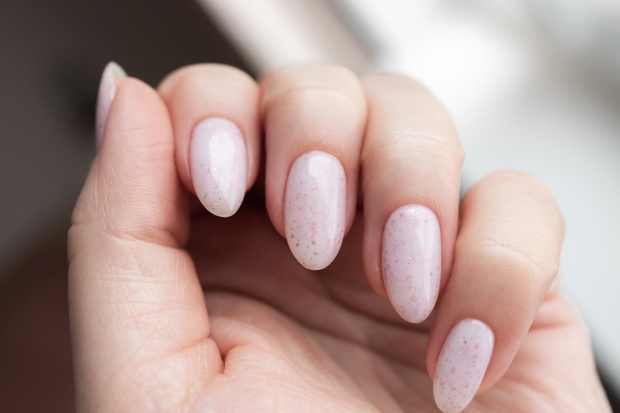 Hand with beautiful manicure - pink gel nails with glitter