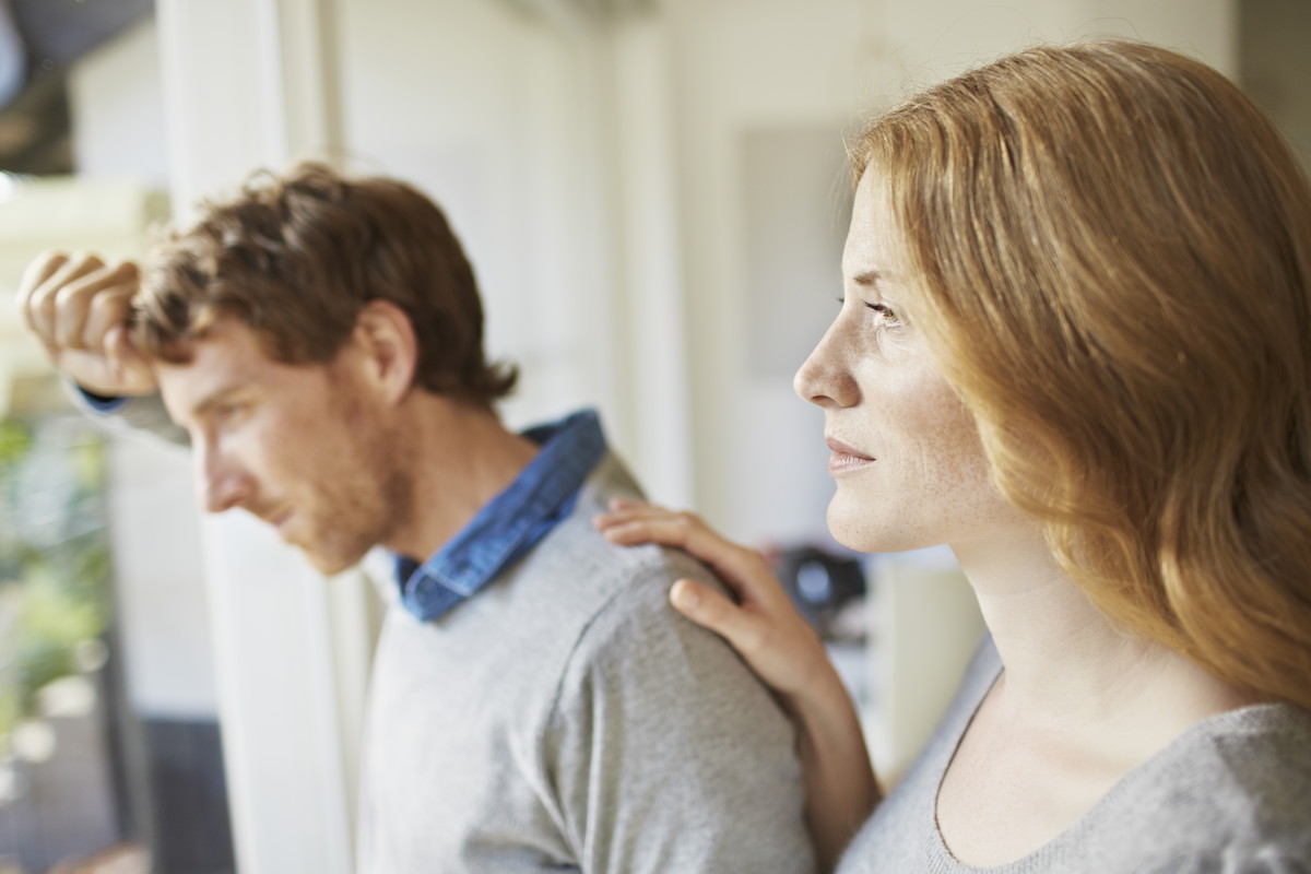 Pensive couple looking out window