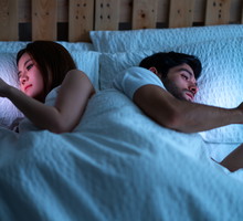 young couple at home in bed late at night using mobile phone in relationship communication problem and internet social media network concept.