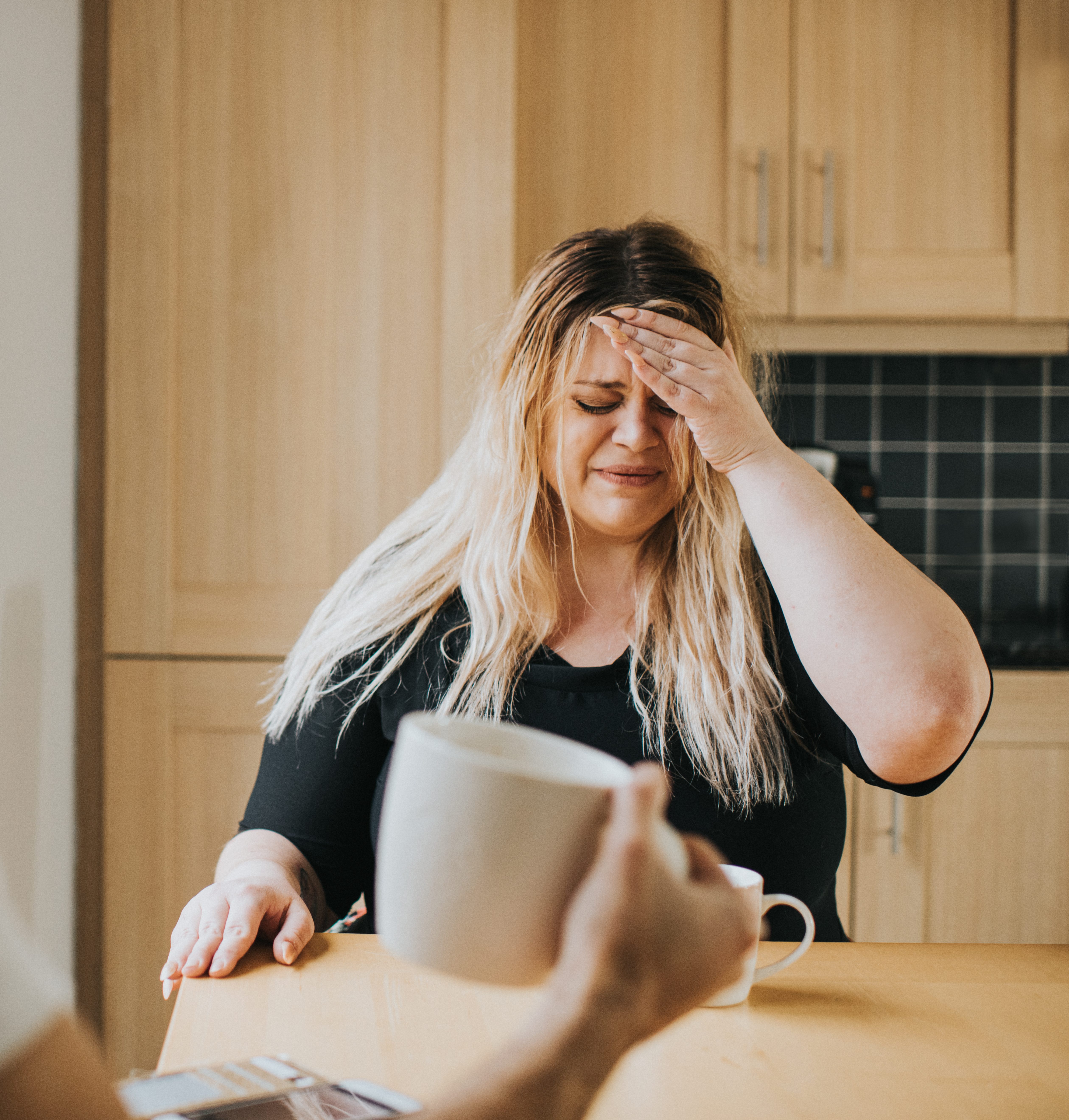 Distressed Woman at a kitchen table talking to her partner