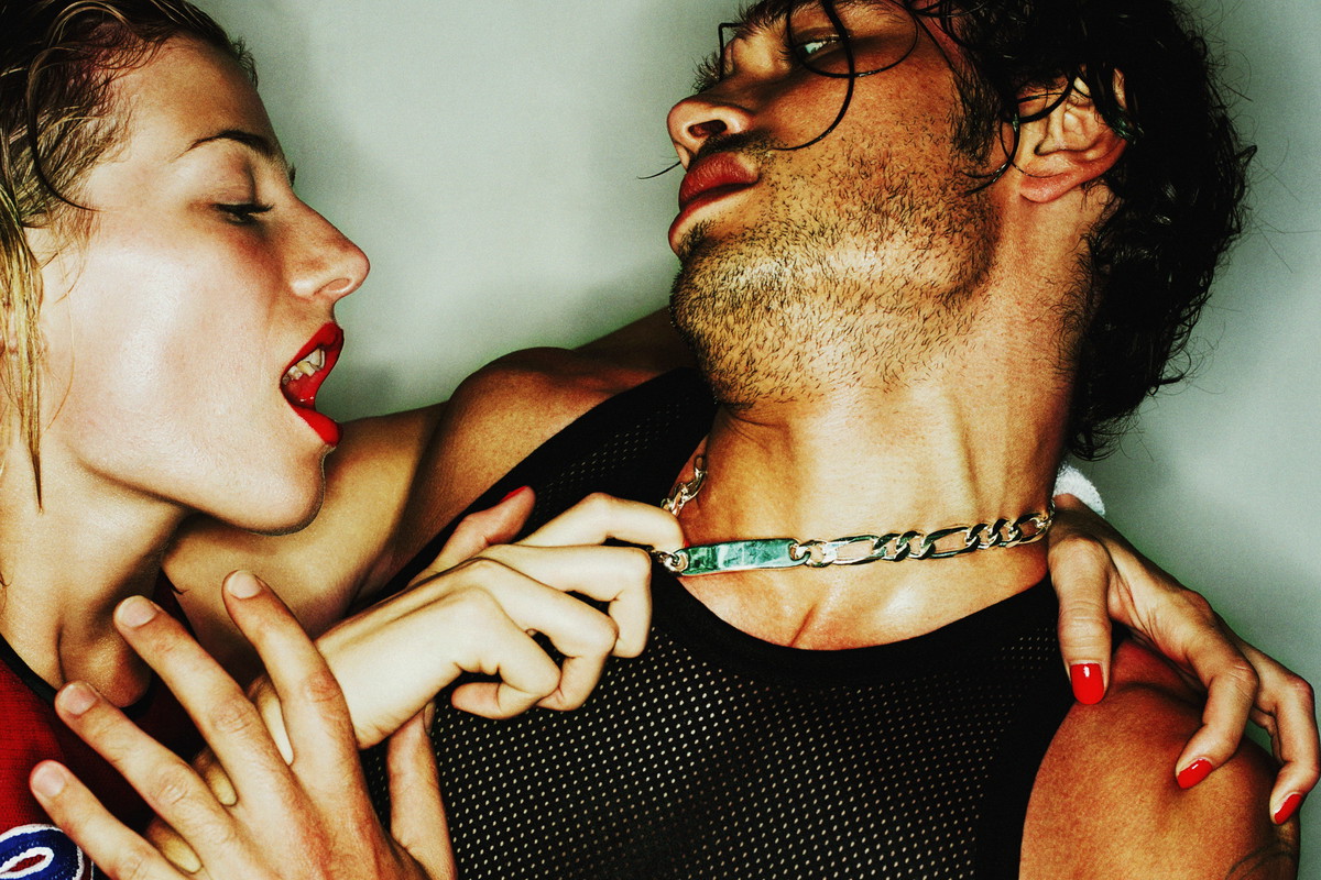 Young couple, woman pulling identity necklace at man's neck