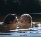 Confident man and delicate woman in problematic relationship swimming in lake, sank under water and looking at each other peeking out of surface with dissatisfied look.