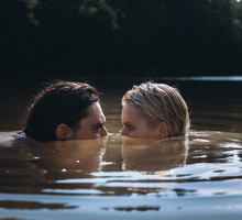 Confident man and delicate woman in problematic relationship swimming in lake, sank under water and looking at each other peeking out of surface with dissatisfied look.