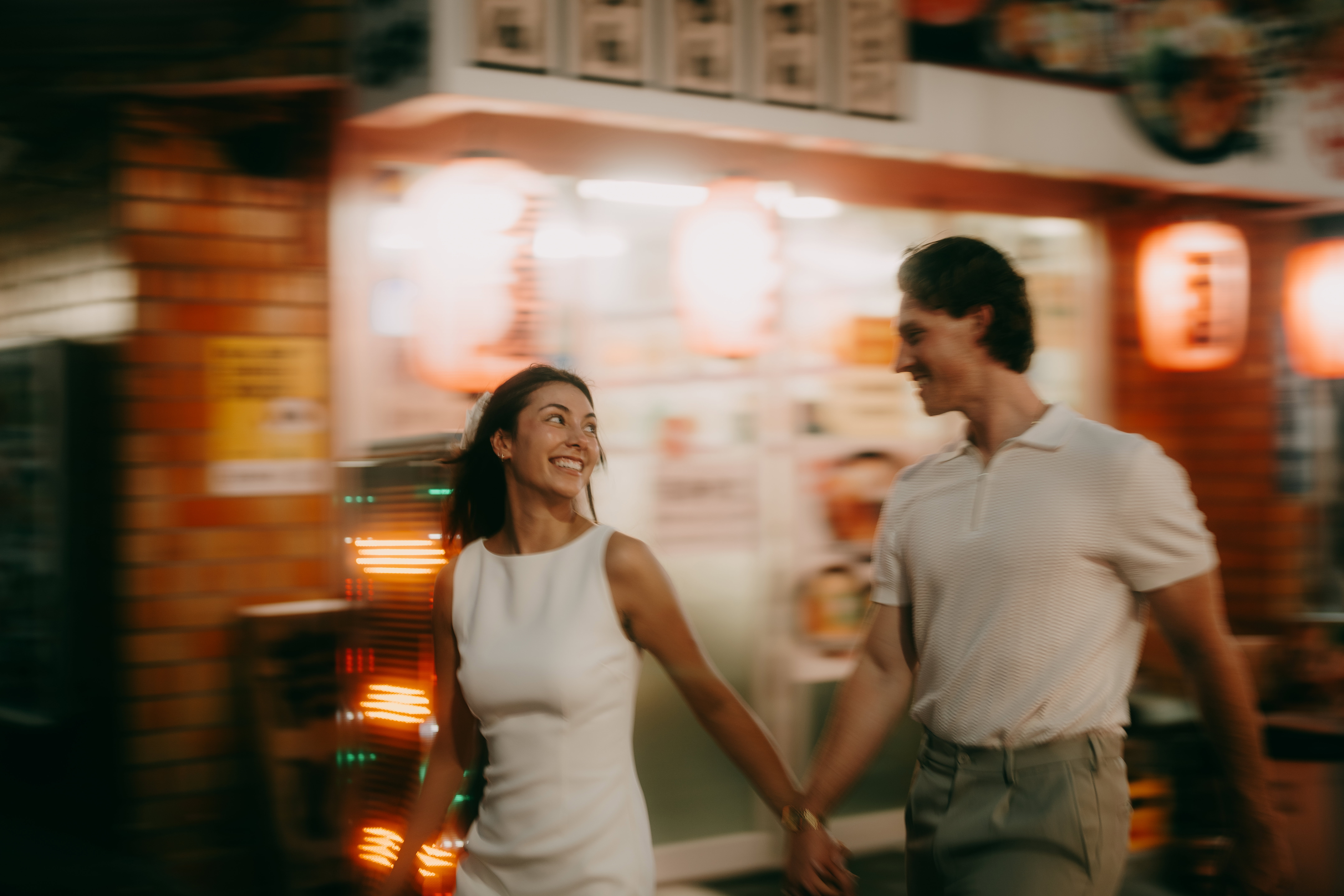 Couple walking through Tokyo backstreet alley with izakaya at night