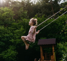 Side view of beautiful girl swinging on garden swing.