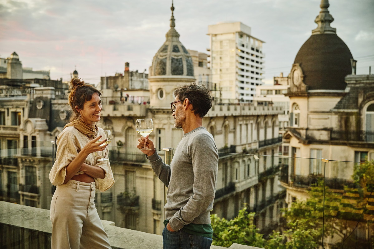 Medium wide shot friends enjoying white wine on rooftop restaurant