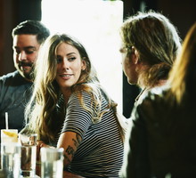 Smiling woman hanging out with friend while having drinks in bar