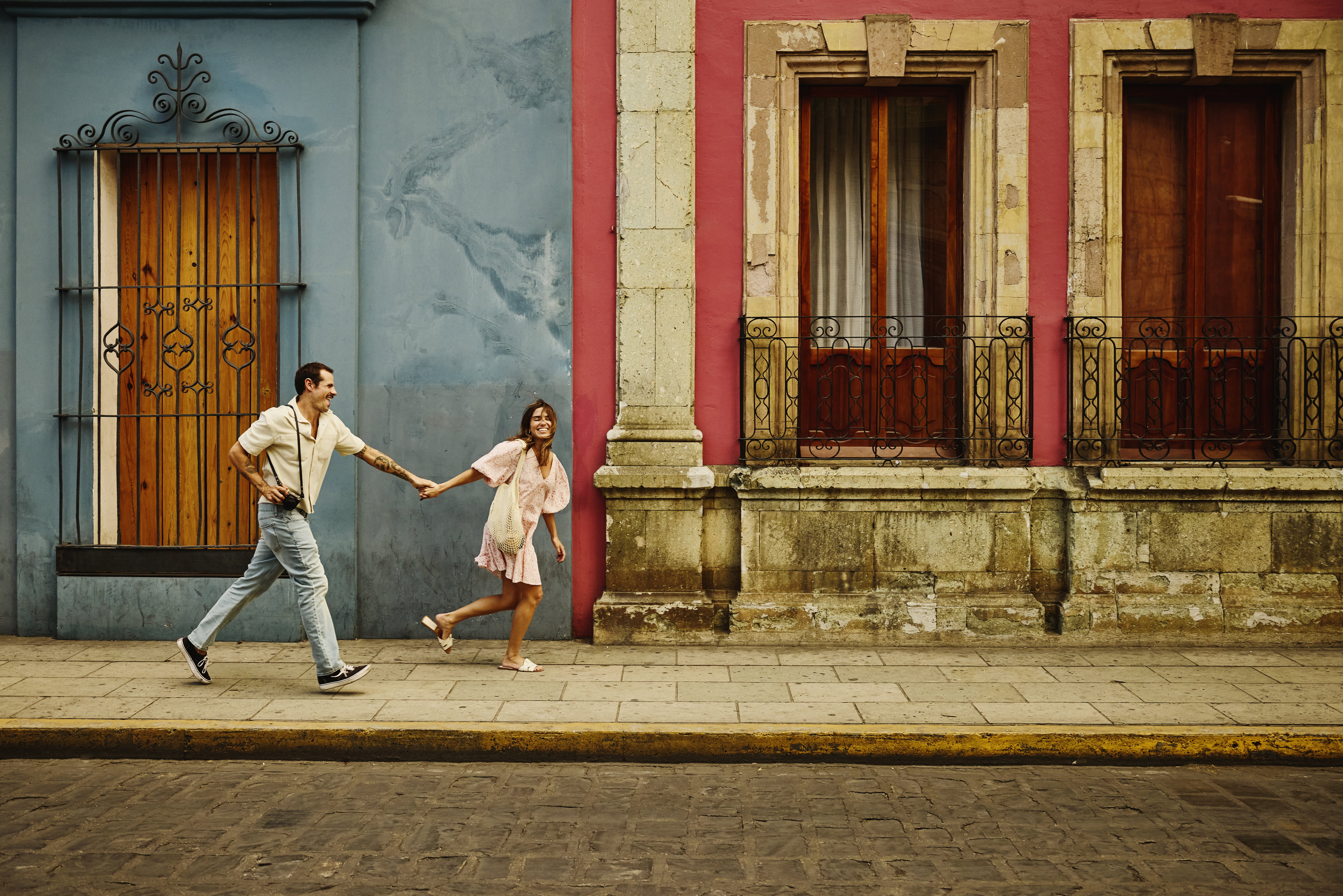 Wide shot tourist couple running through the streets of old Oaxaca
