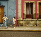 Wide shot tourist couple running through the streets of old Oaxaca
