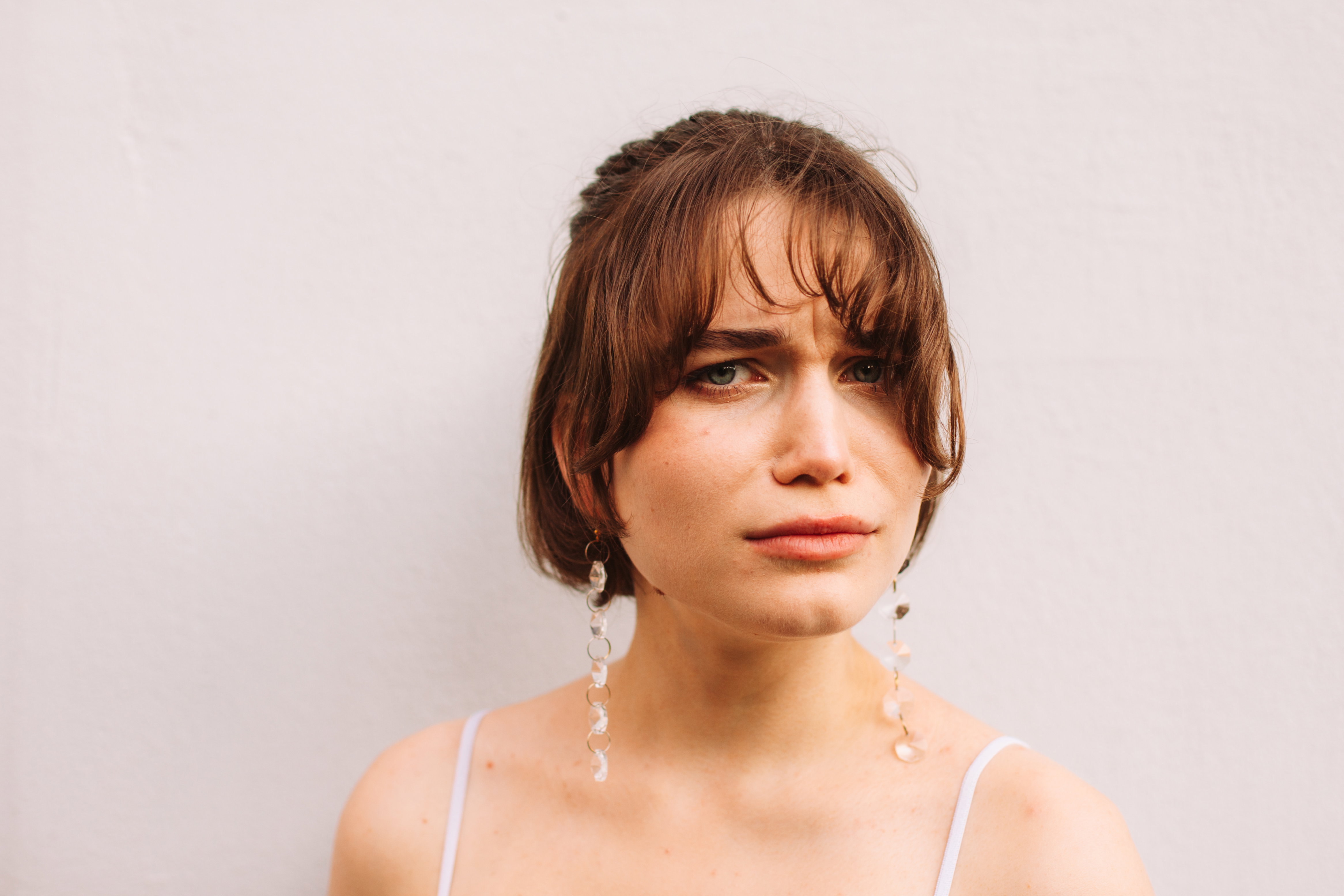 Portrait of serious young woman standing against gray wall