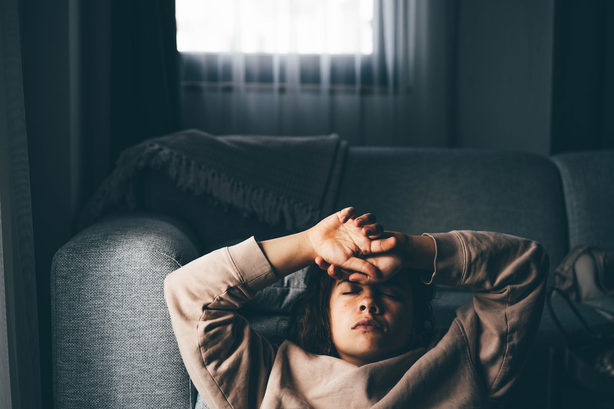 Sad and depressed woman sitting on sofa at home.