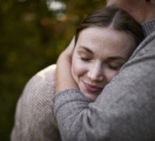 Grandmother embracing adult granddaughter in garden