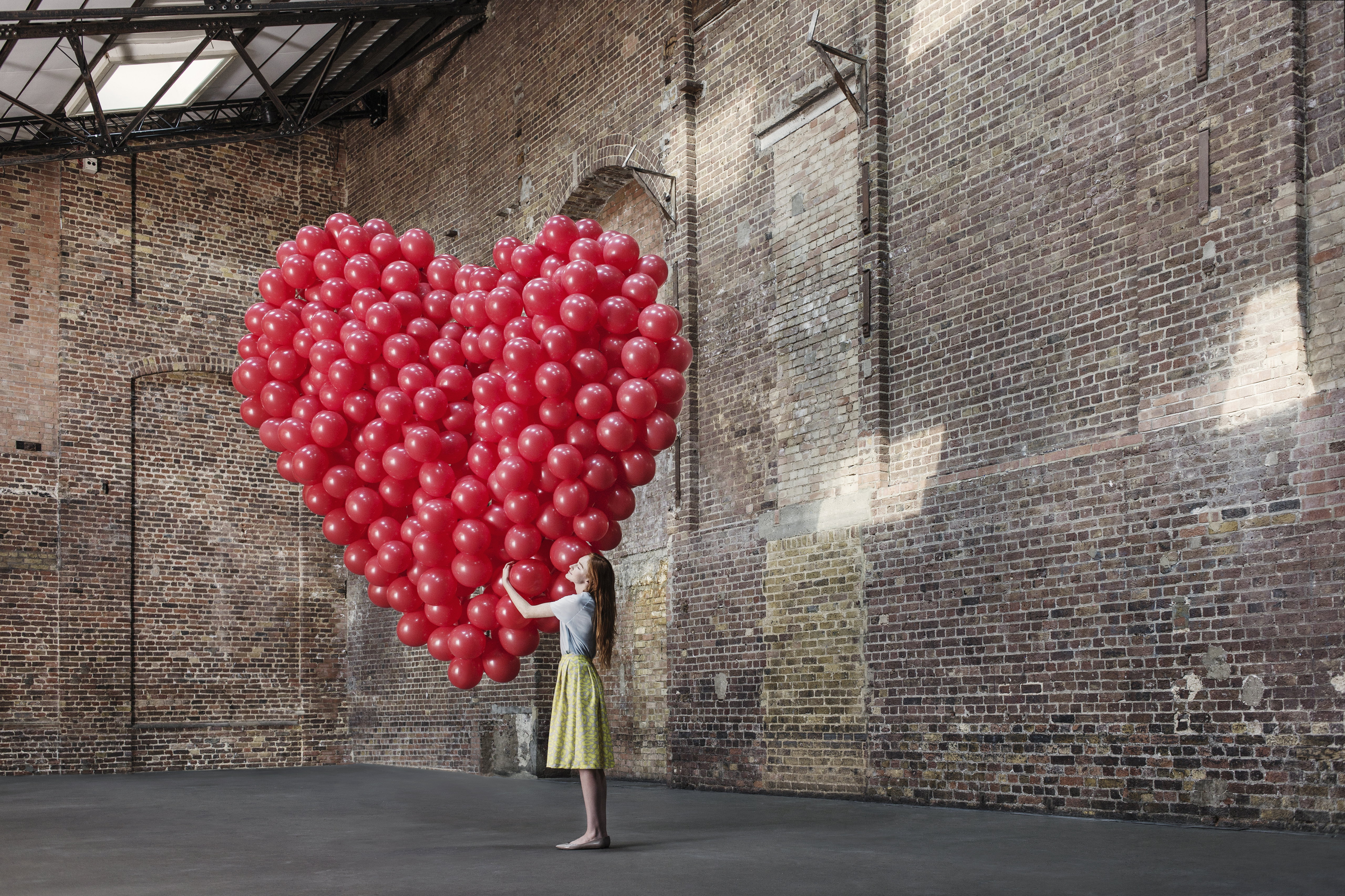 Woman in warehouse with heart made of balloons