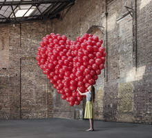 Woman in warehouse with heart made of balloons
