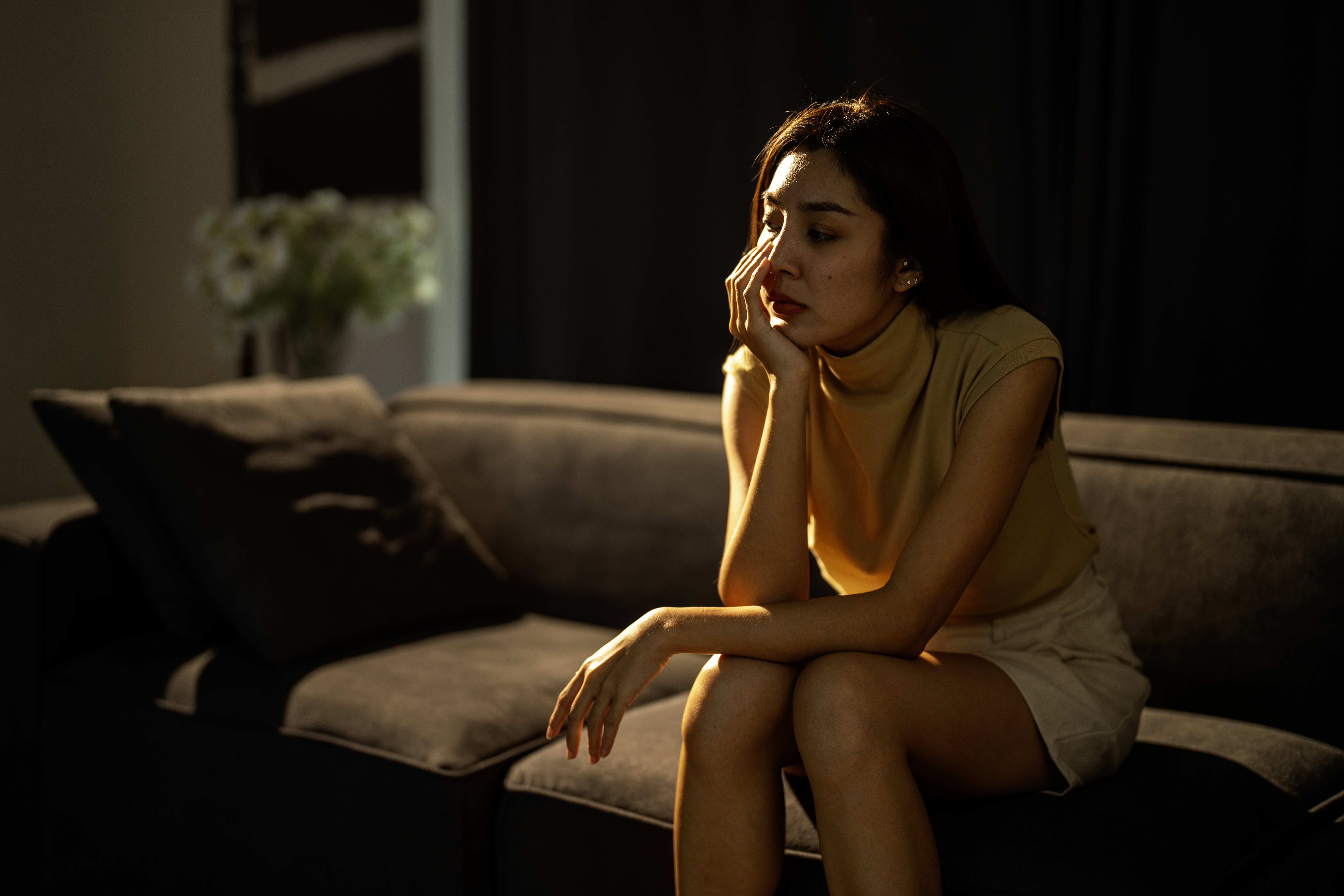 Sad woman sitting on couch alone at home