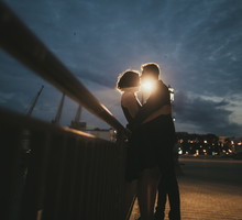 Caucasian couple kissing near railing at night