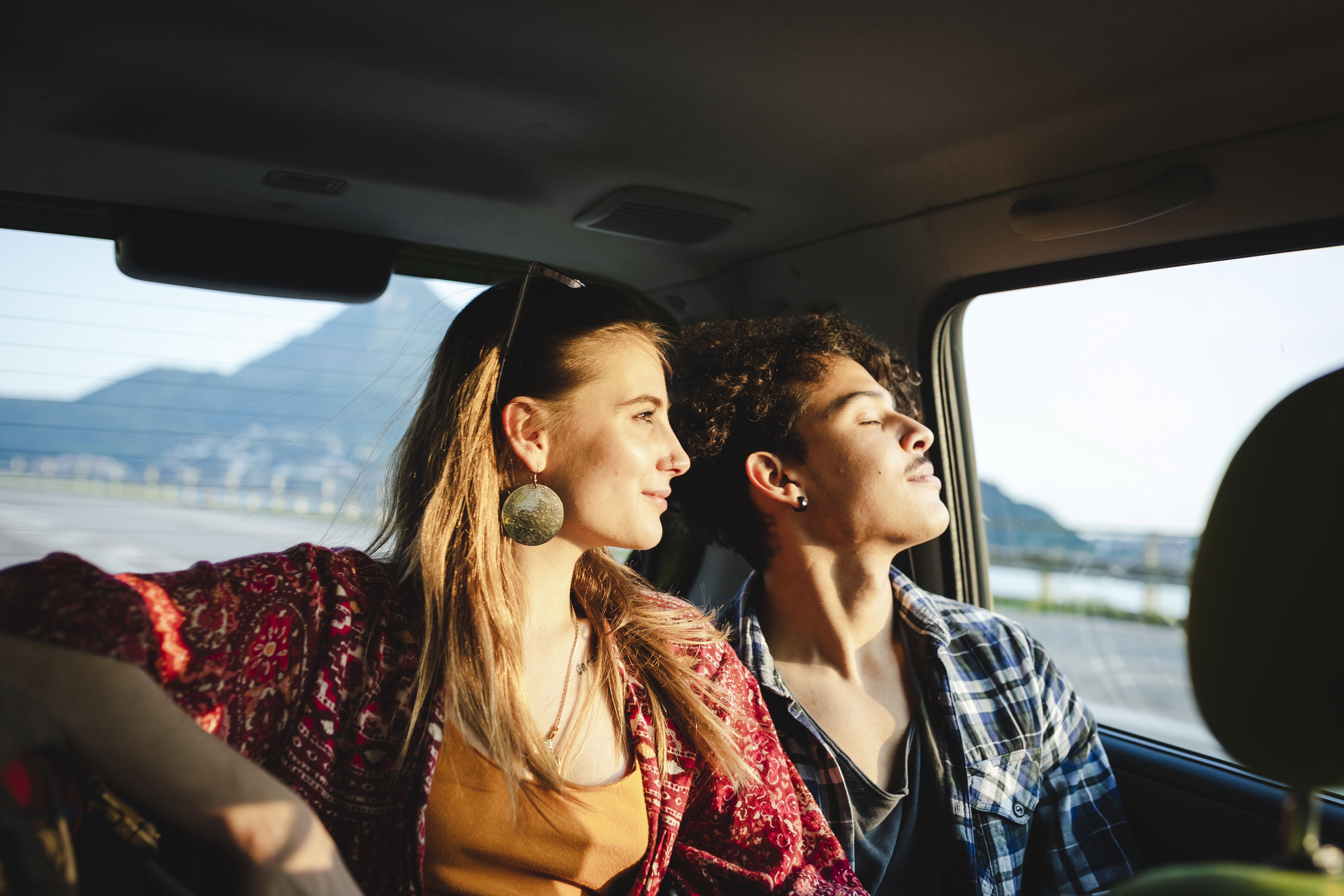 Young couple traveling by car, sunset light