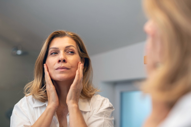 Mature woman checking skin while looking in bathroom mirror