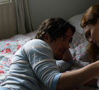 Couple lying on bed, man holding woman's shoulder