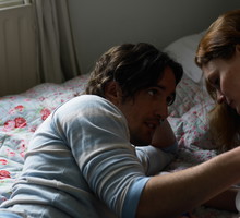 Couple lying on bed, man holding woman's shoulder
