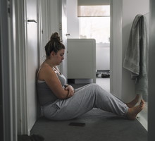 Teenage girl sitting on landing floor with her smartphone beside her - negative emotion