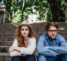Couple after argument sitting on concrete stairs in city.