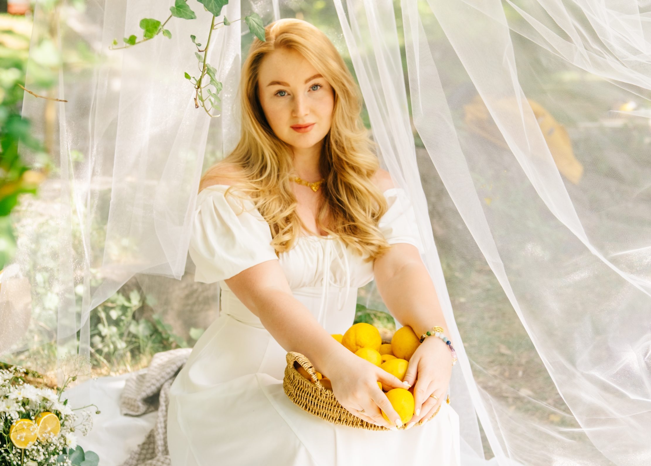 Romantic blonde woman with basket of lemons enjoying aesthetic outdoor picnic