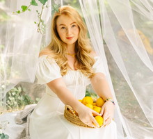 Romantic blonde woman with basket of lemons enjoying aesthetic outdoor picnic