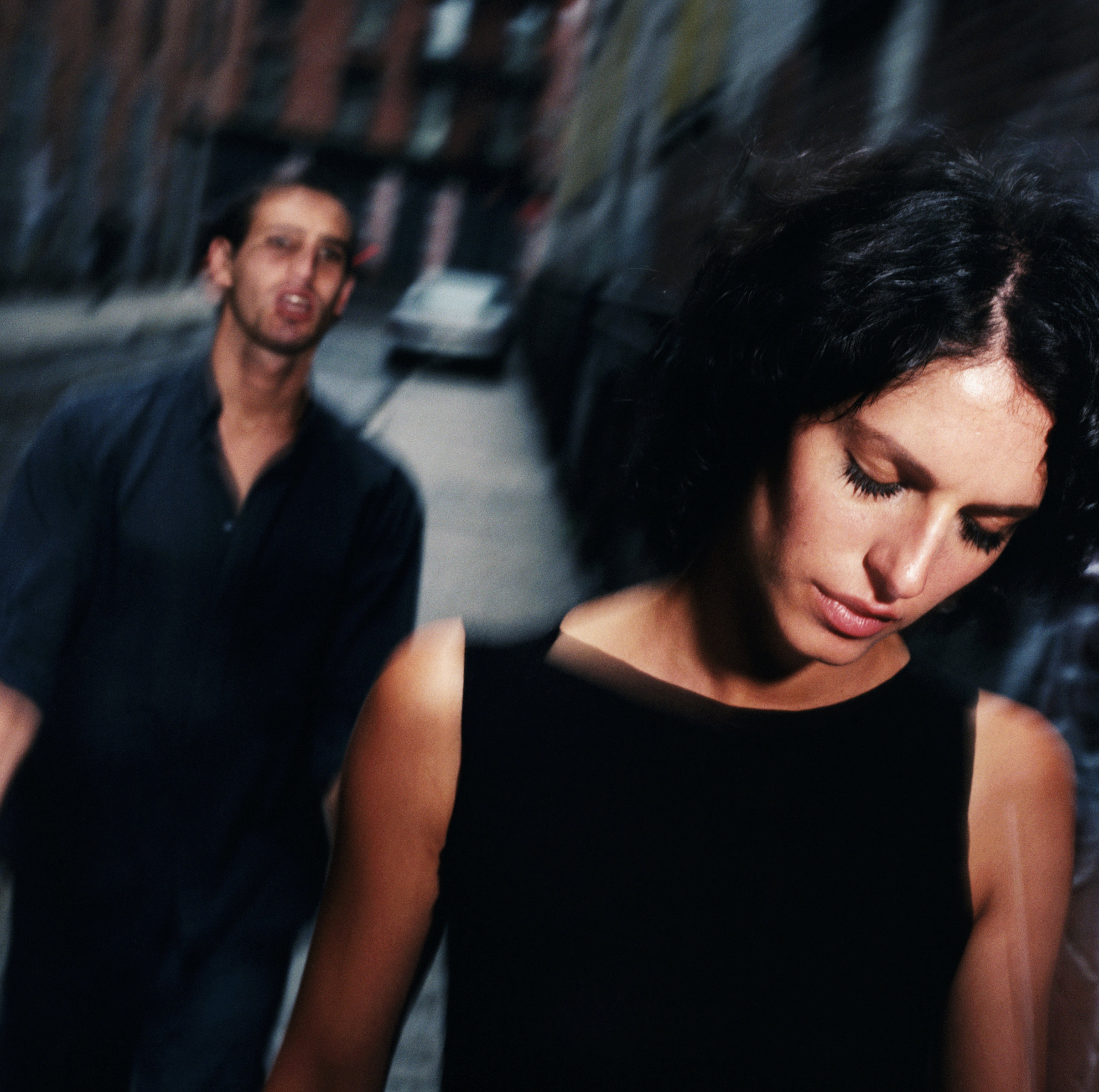 Young man following woman along street (blurred motion)