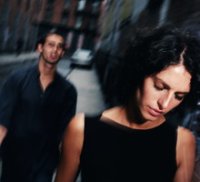 Young man following woman along street (blurred motion)