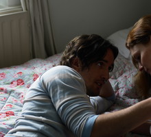 Couple lying on bed, man holding woman's shoulder