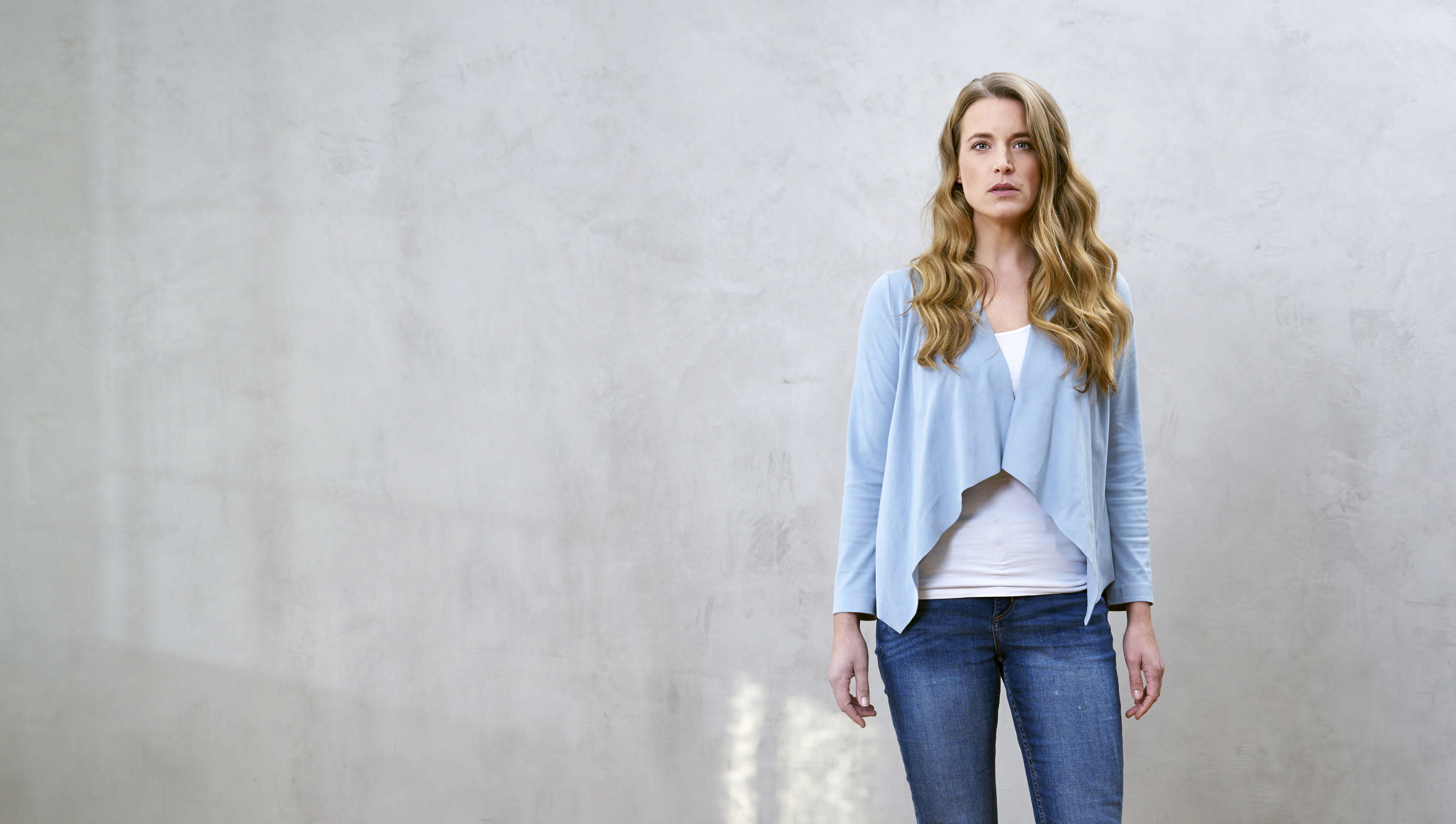 Portrait of serious blond woman in front of grey wall