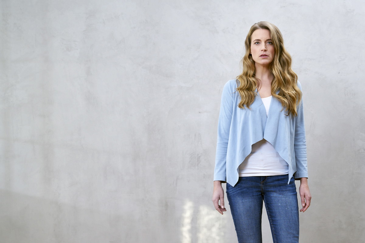 Portrait of serious blond woman in front of grey wall