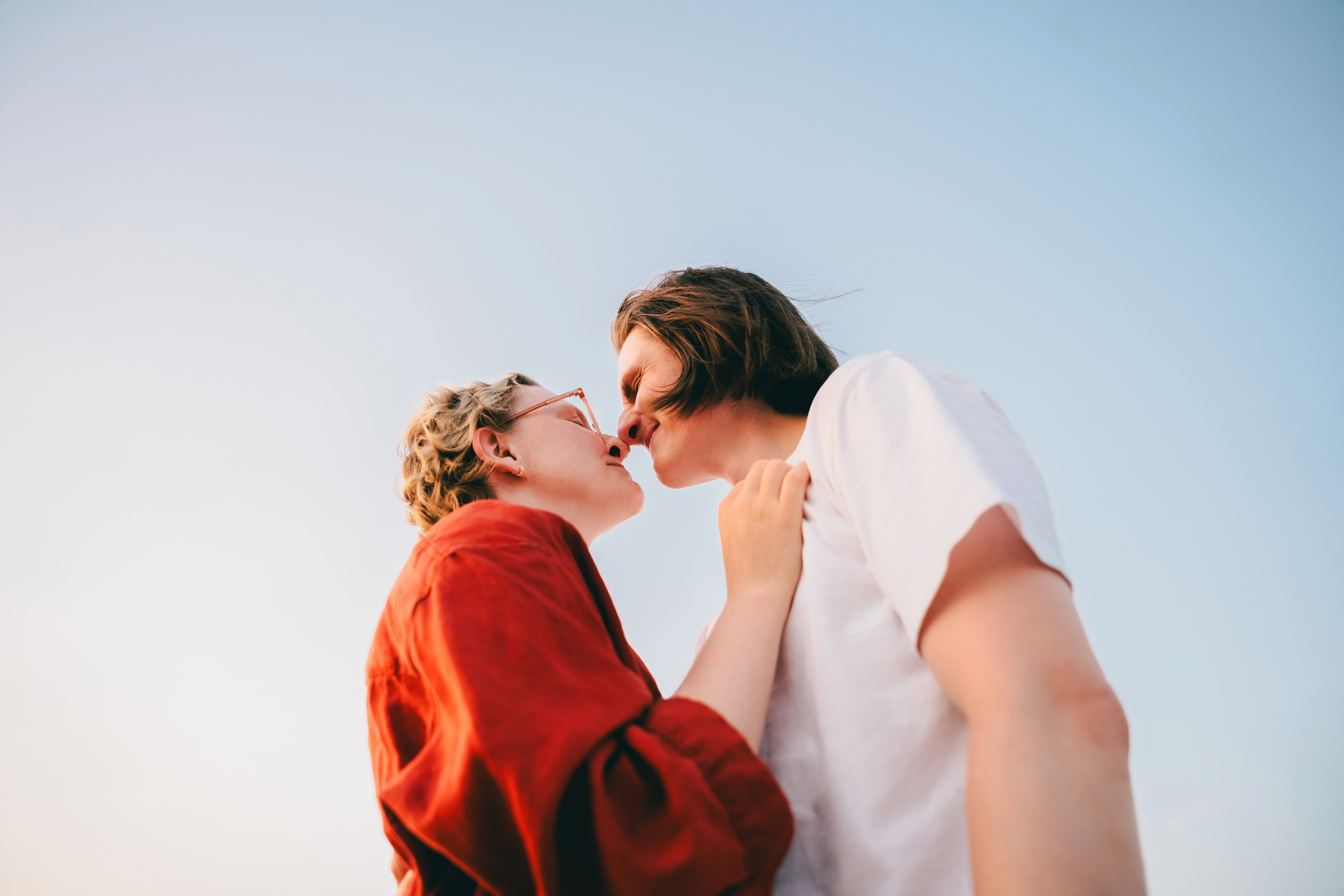 A romantic couple shares an intimate moment under a clear blue sky