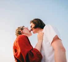 A romantic couple shares an intimate moment under a clear blue sky