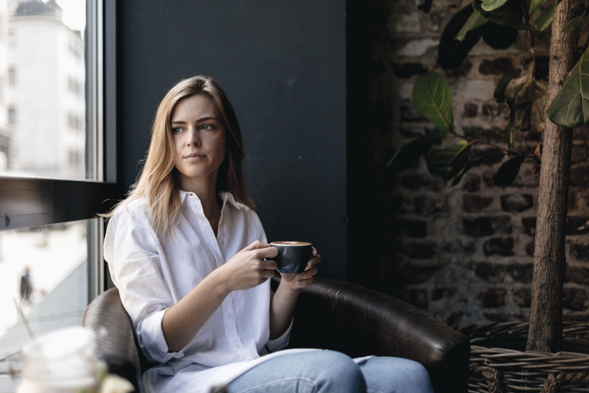 Young woman sitting in cafe, drinking coffee