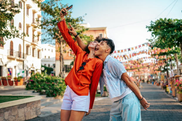 Young students relaxing and enjoying a city break, using their mobile phone to capture a moment