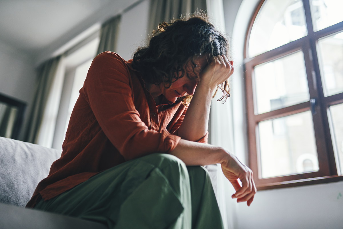 Distressed Woman Sitting on a Sofa in a Sunny Apartment