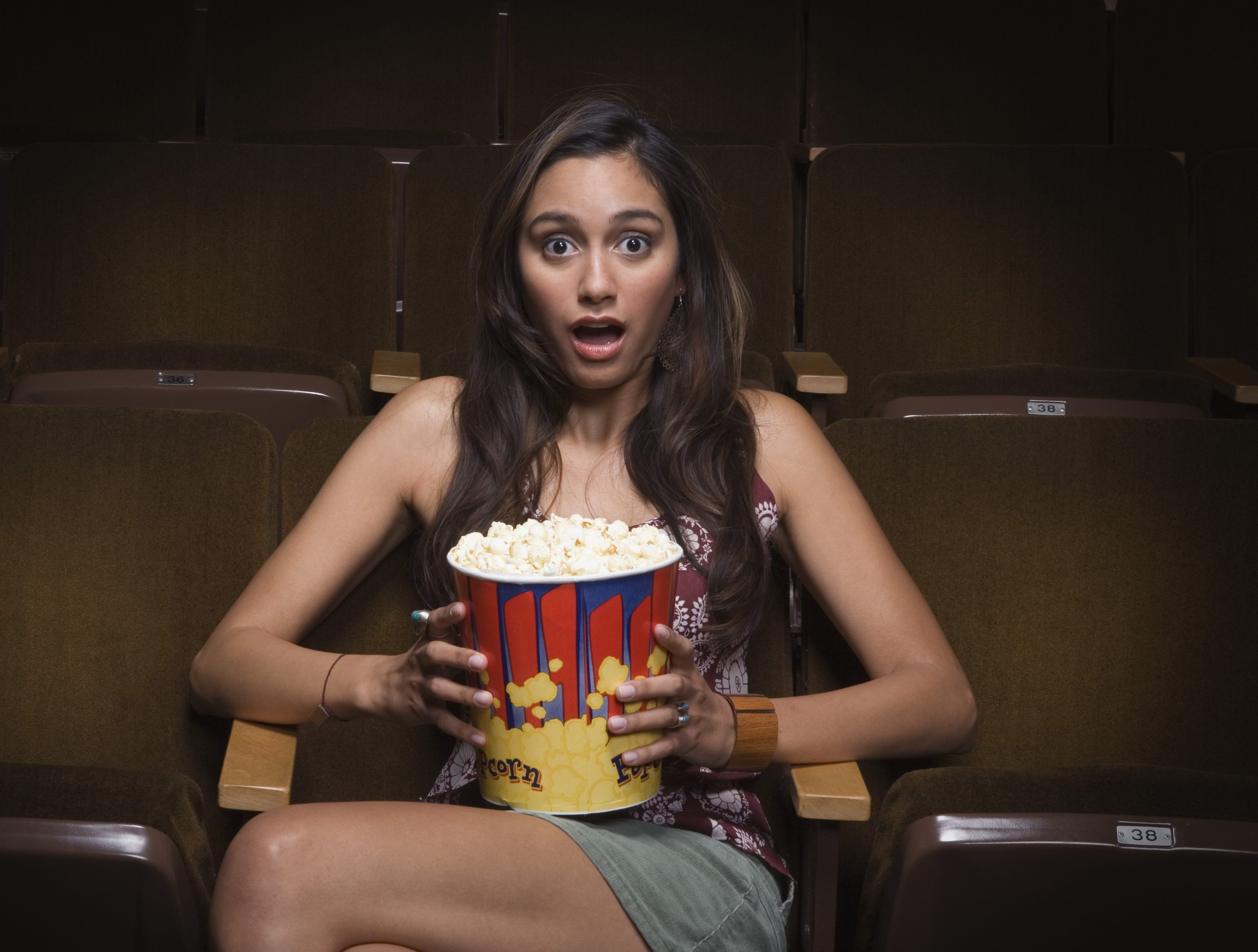 Scared woman sitting in movie theater