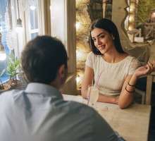 Portrait of smiling young woman talking to her boyfriend in a restaurant
