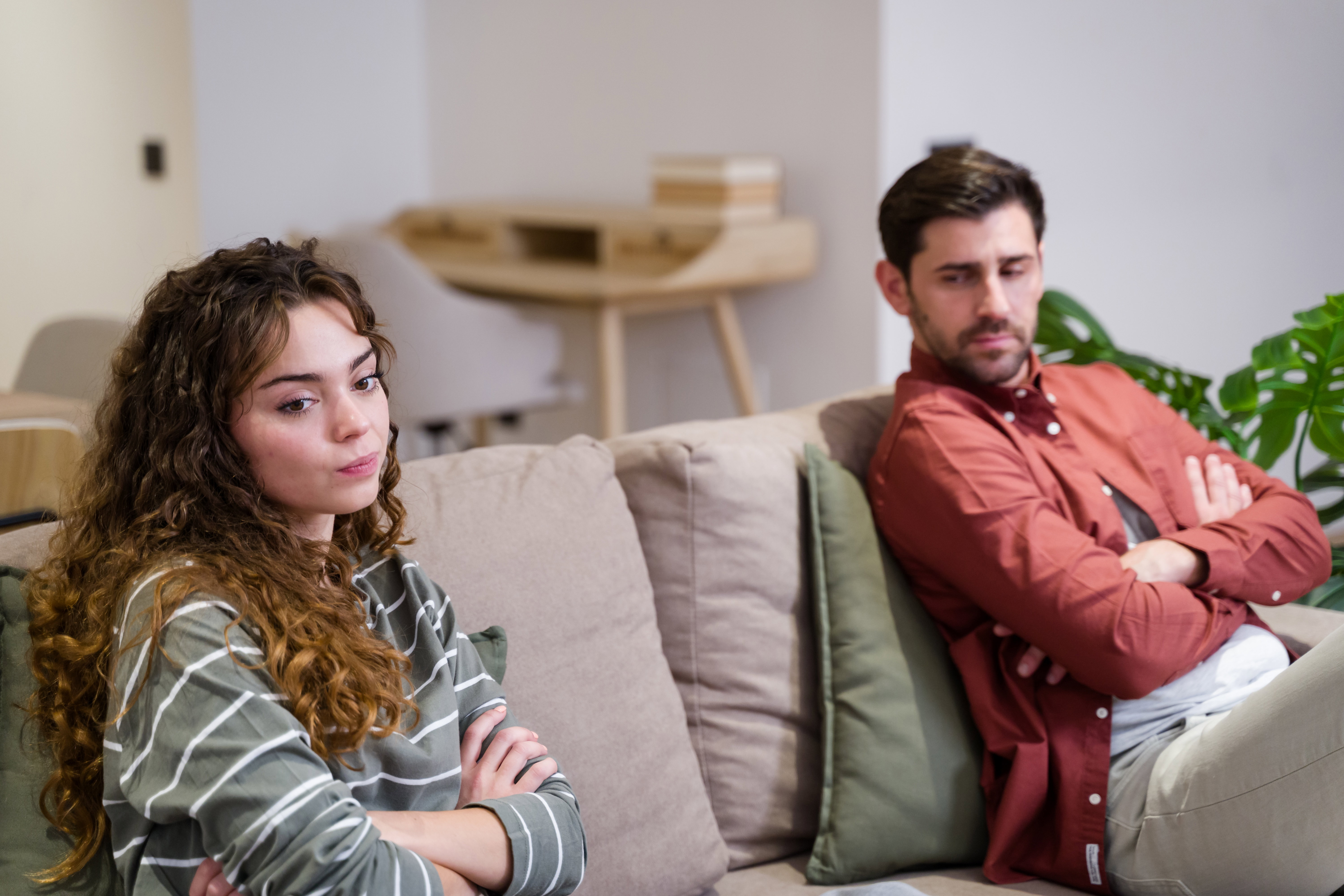 Young couple sitting on sofa at home having relationship problems
