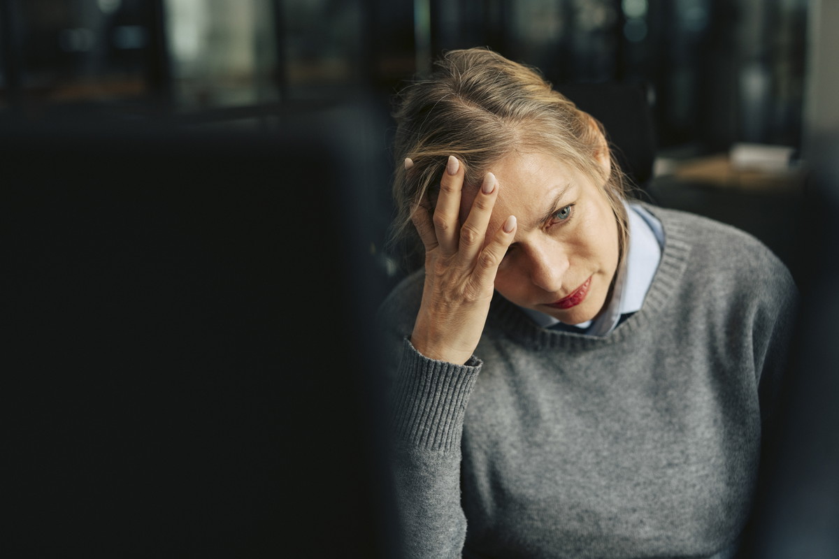 Depressed senior businesswoman with head in hand at office