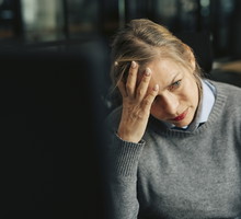 Depressed senior businesswoman with head in hand at office