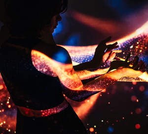 Woman’s hands in dark and projection of abstract light waves on them.