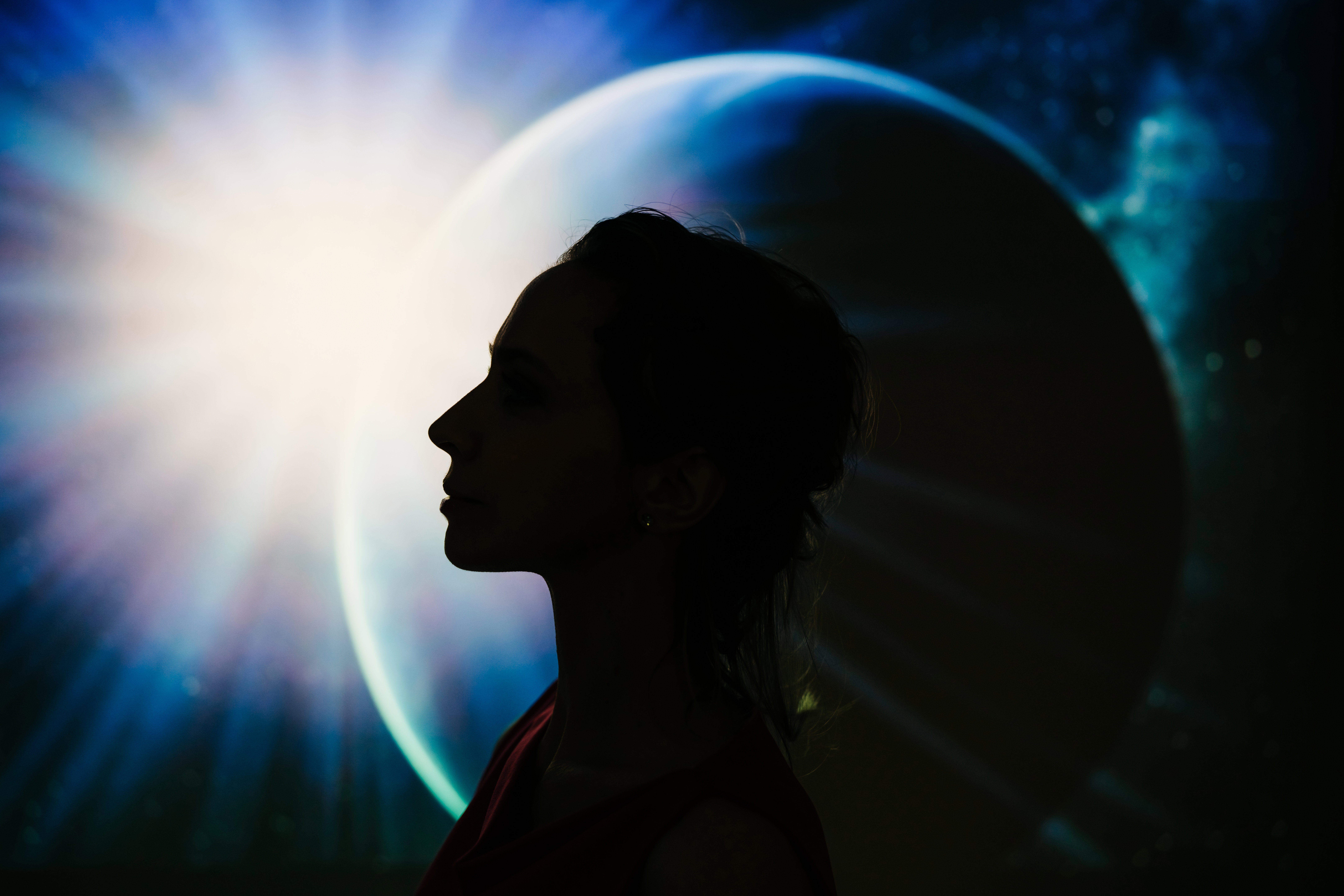 A silhouette of a woman’s profile against a cosmic background featuring a planet and a bright star.