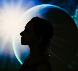 A silhouette of a woman’s profile against a cosmic background featuring a planet and a bright star.