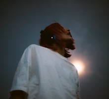 Young woman listening music in headphones standing against the sky at night