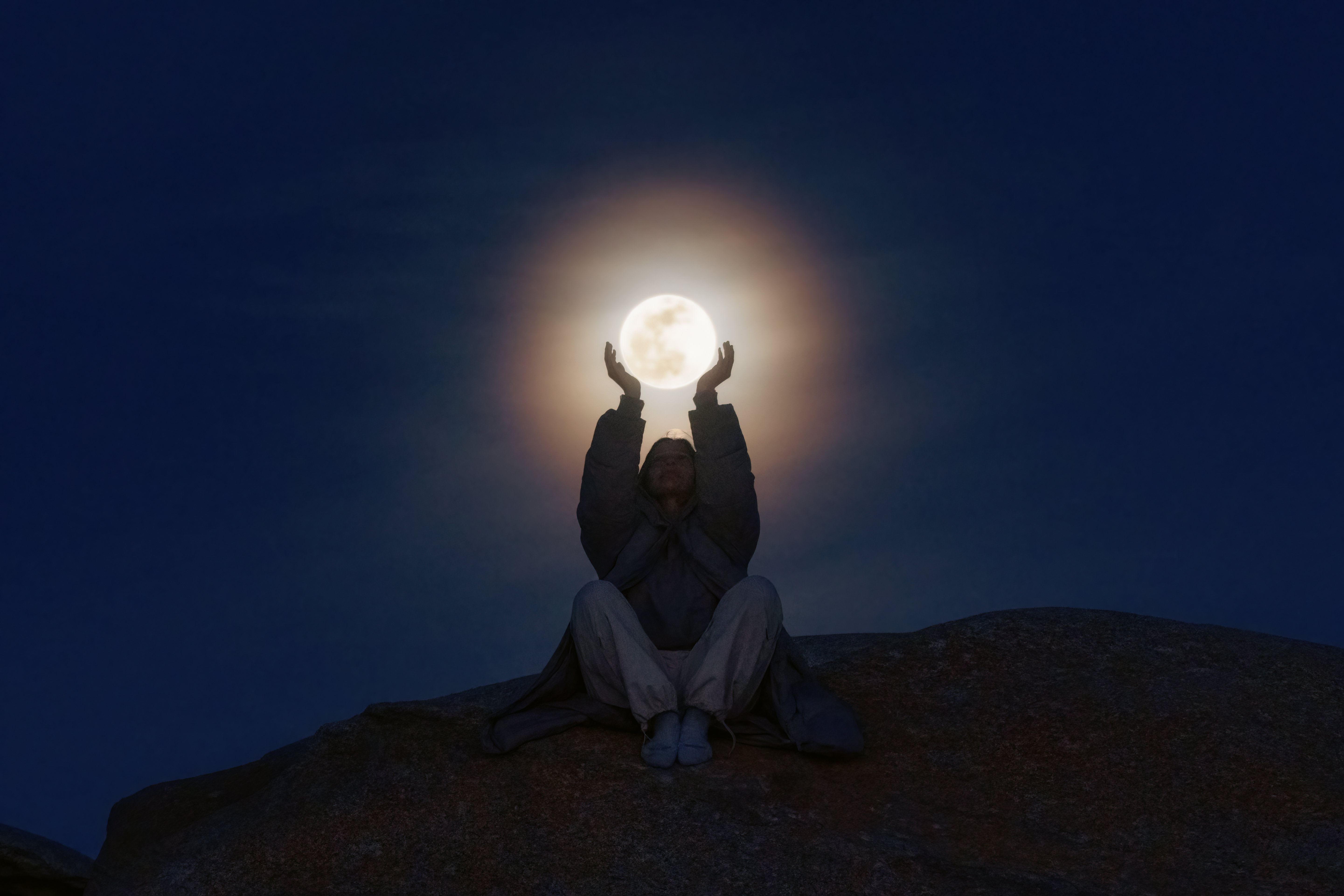 Young woman holding the full moon in her hands, Incredible photograph of a young woman catching the moon with her hands.