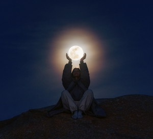 Young woman holding the full moon in her hands, Incredible photograph of a young woman catching the moon with her hands.