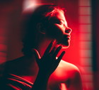 A woman doing full body red light therapy in a dark room